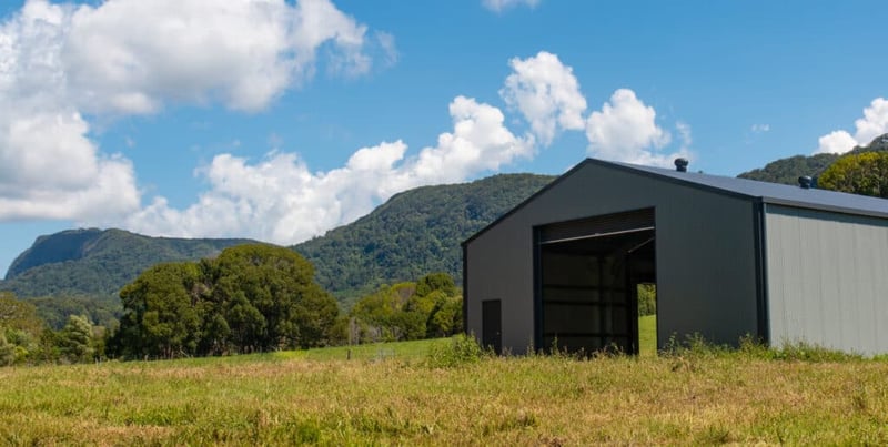 A big metal barn in a green field