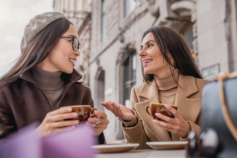 Two young women a talking and drinking coffee together